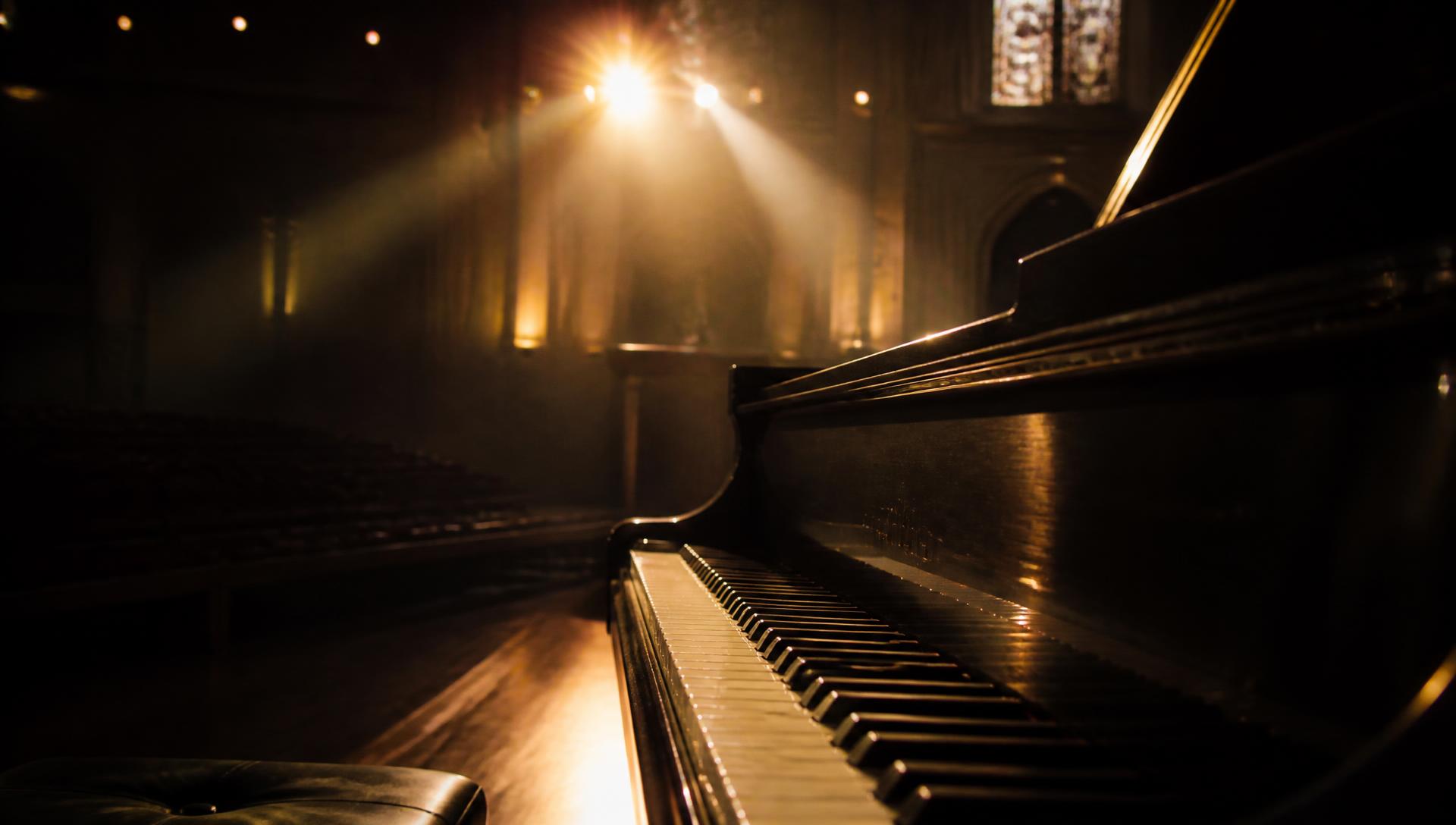 Mains posées sur les touches d'un piano dans une église faiblement éclairée